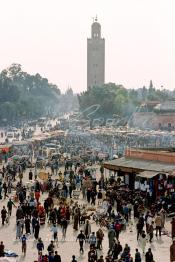 Image du Maroc Professionnelle de  Les calèches de jus d'orange sont bien alignés sur La mythique place Jemaa El Fana, avec ses charmeurs de serpents, lieu incontournable de Marrakech, la ville touristique du Maroc, au fond le minaret de la Koutoubia, Jeudi 19 Mai 1988. (Photo / Abdeljalil Bounhar)